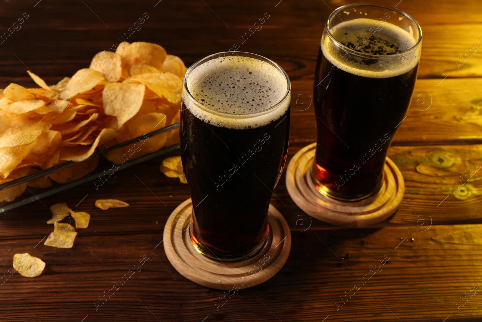 Photo of Glasses of beer and potato chips on wooden table