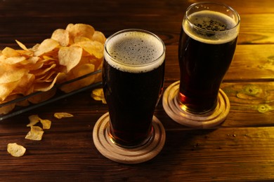 Glasses of beer and potato chips on wooden table