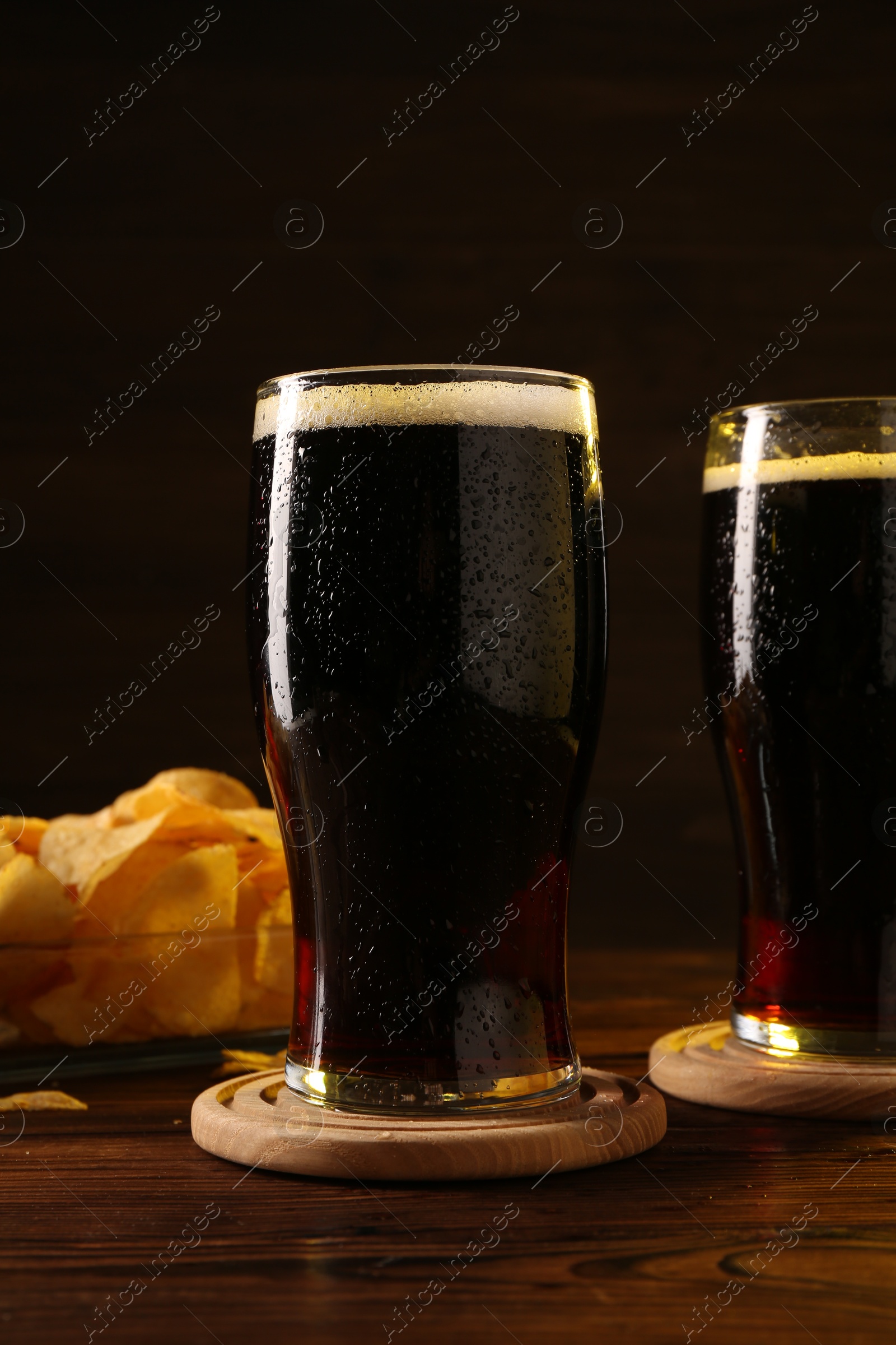 Photo of Glasses of beer and potato chips on wooden table