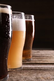 Photo of Glasses with different types of beer on wooden table, closeup