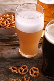 Photo of Glasses of beer and pretzel crackers on wooden table, closeup