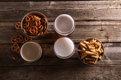 Photo of Glasses of beer, pretzel crackers and rusks on wooden table, flat lay