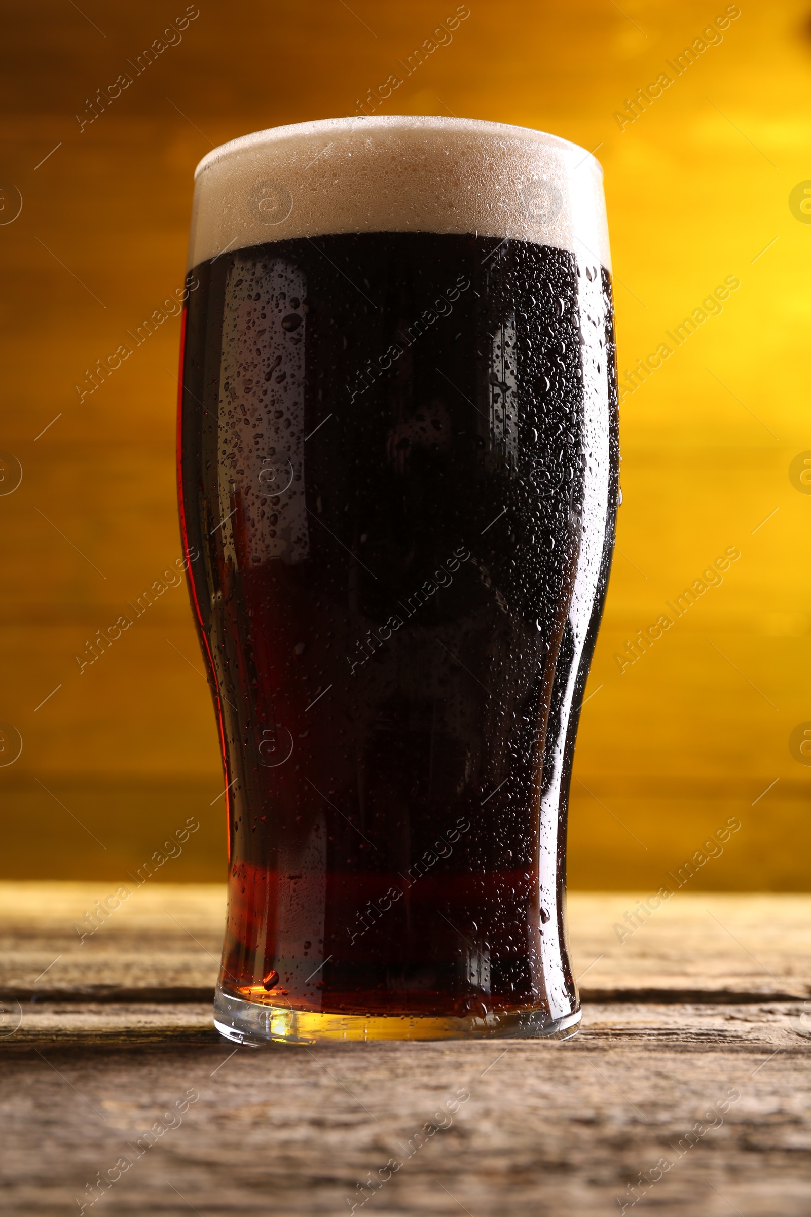 Photo of Glass of beer with froth on wooden table