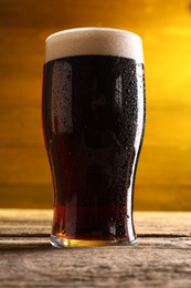 Glass of beer with froth on wooden table