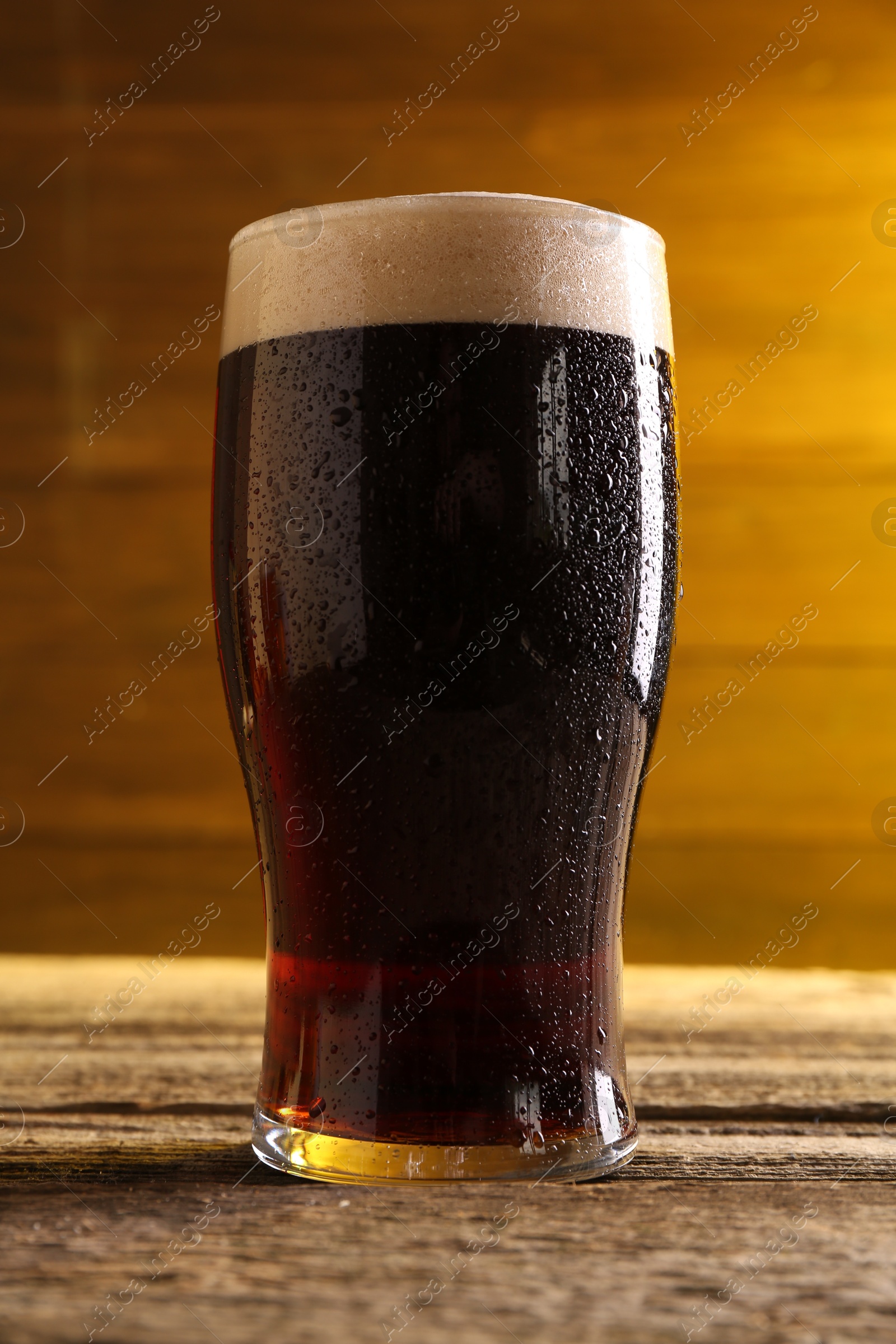 Photo of Glass of beer with froth on wooden table