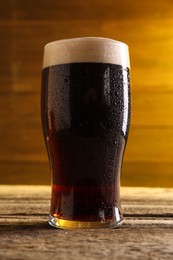 Photo of Glass of beer with froth on wooden table