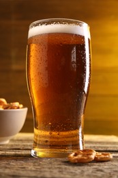 Glass of beer and pretzel crackers on wooden table