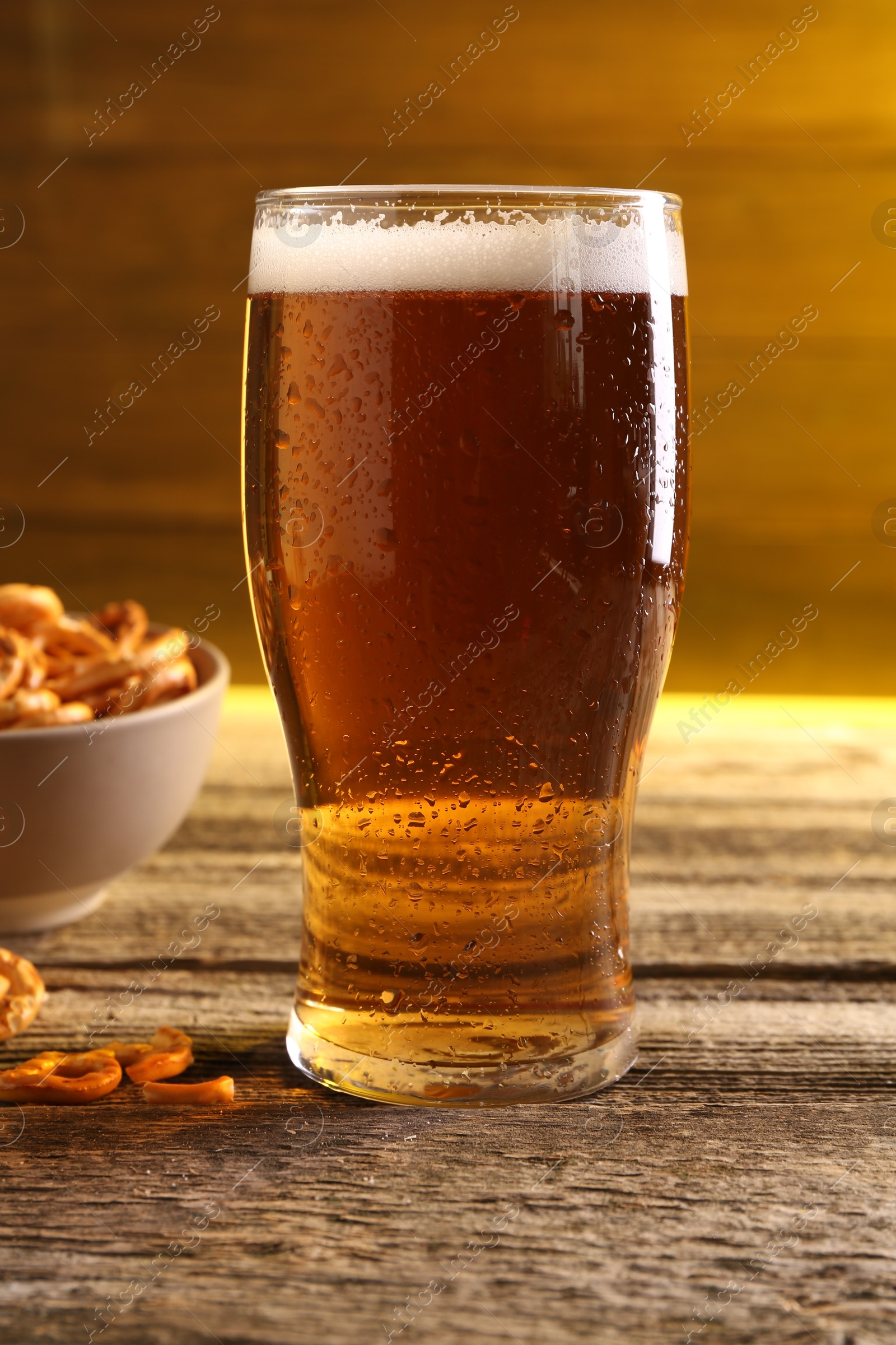 Photo of Glass of beer and pretzel crackers on wooden table