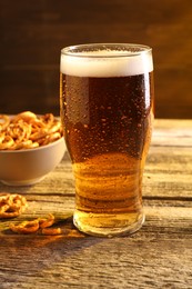Photo of Glass of beer and pretzel crackers on wooden table