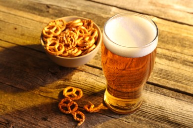 Photo of Glass of beer and pretzel crackers on wooden table