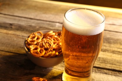 Glass of beer and pretzel crackers on wooden table, closeup