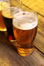 Glasses with different types of beer on wooden table, closeup