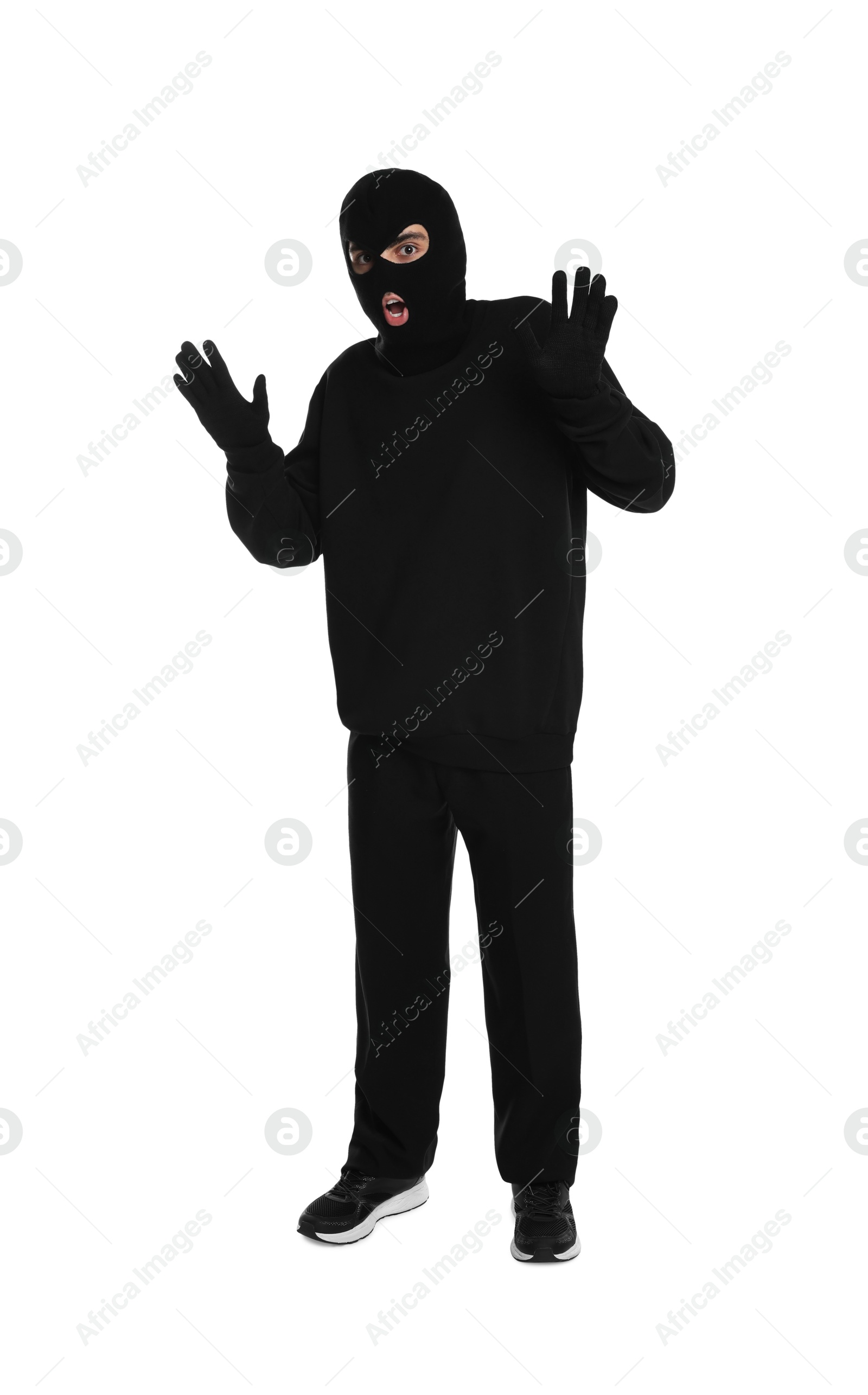 Photo of Emotional thief in balaclava raising hands on white background