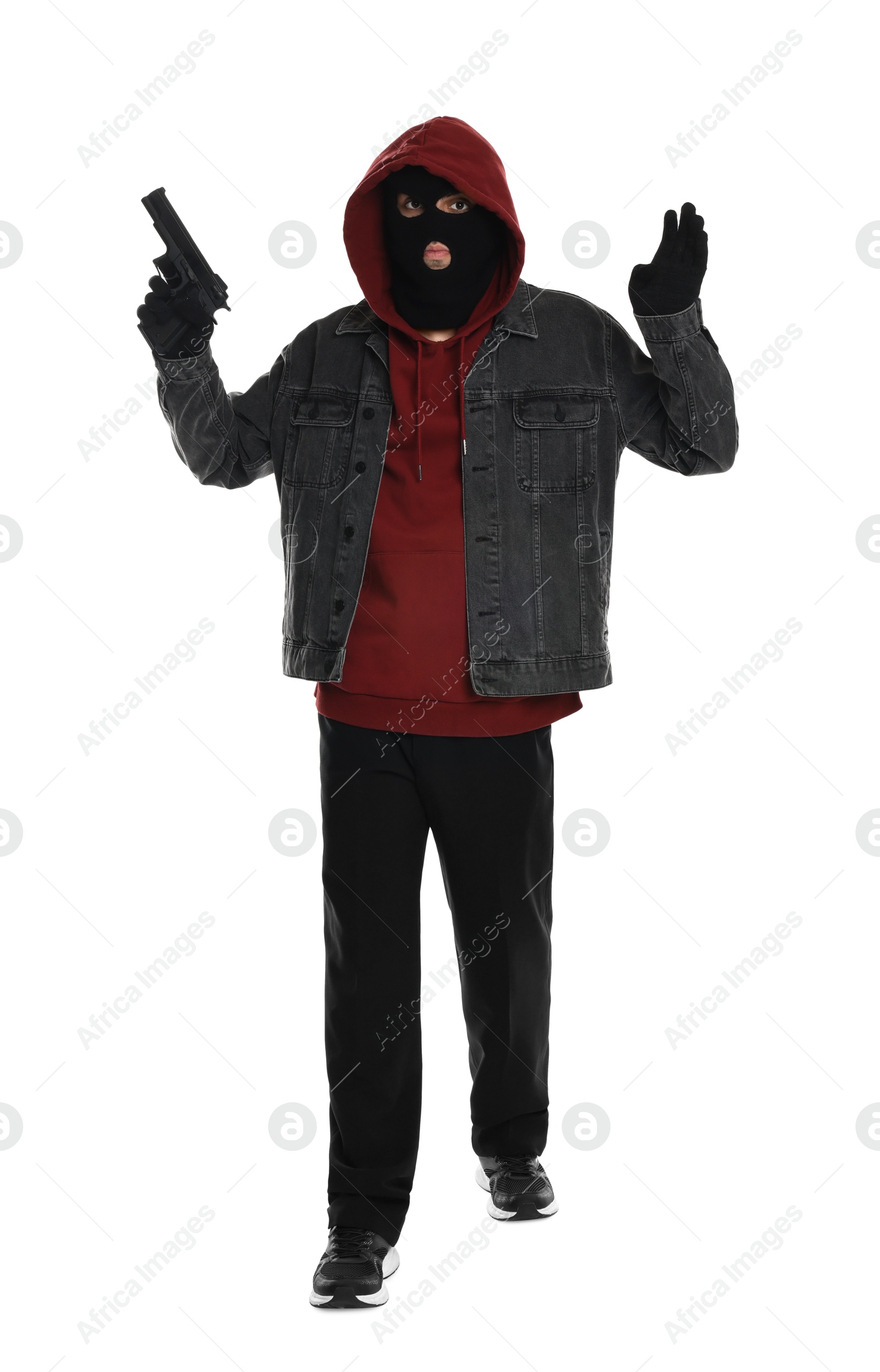 Photo of Thief in balaclava raising hands with gun on white background