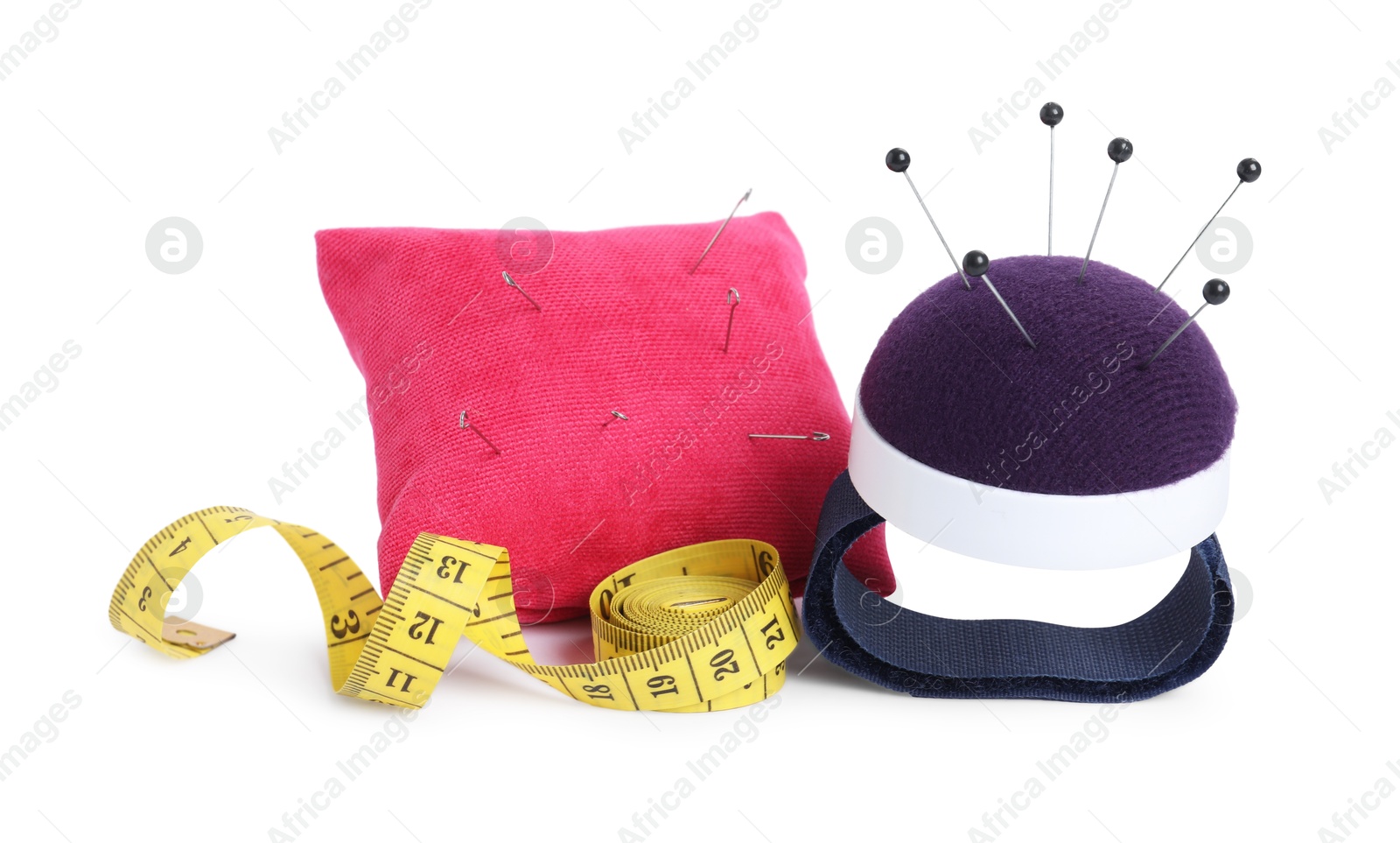 Photo of Pincushions with sewing needles, pins and measuring tape isolated on white