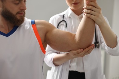 Photo of Sports injury. Doctor examining patient's hand in hospital, closeup