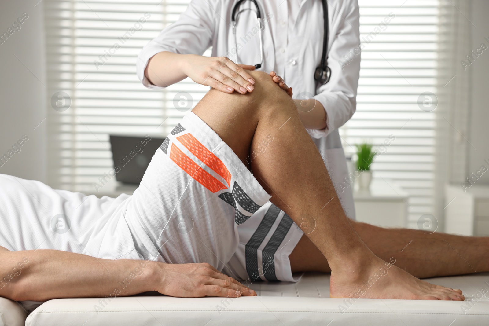 Photo of Sports injury. Doctor examining patient's knee in hospital, closeup