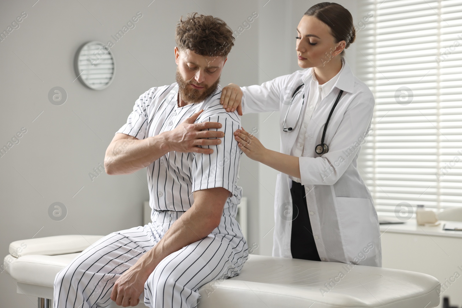 Photo of Sports injury. Doctor examining patient's shoulder in hospital