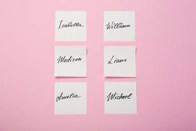 Photo of Paper stickers with different names on pink background, flat lay. Choosing baby's name