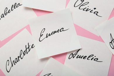 Photo of Paper stickers with different names on pink background, top view. Choosing baby's name