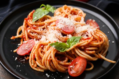 Tasty pasta with tomato sauce, cheese and basil on table, closeup