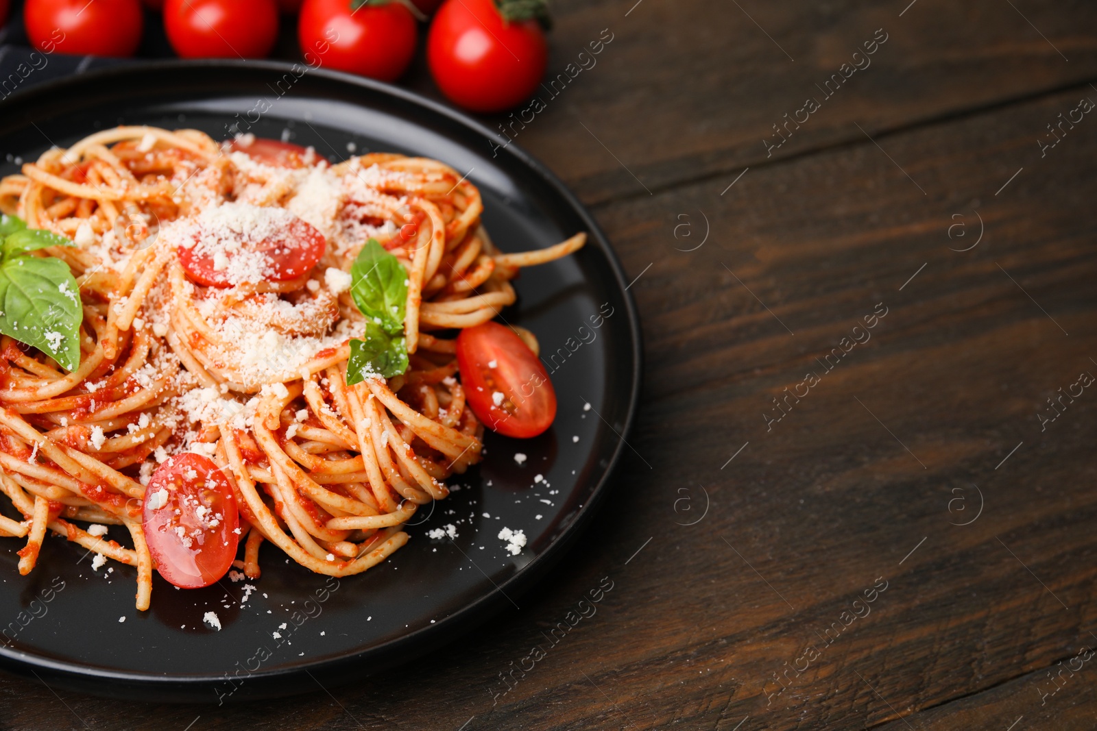 Photo of Tasty pasta with tomato sauce, cheese and basil on wooden table, space for text