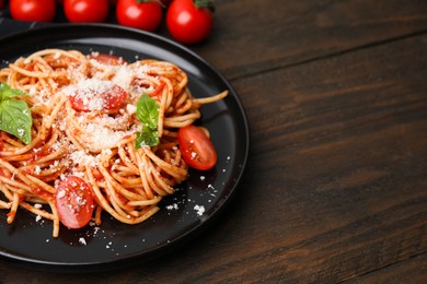 Tasty pasta with tomato sauce, cheese and basil on wooden table, space for text