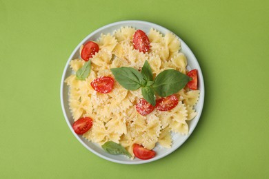 Photo of Tasty pasta with tomato, cheese and basil on green table, top view