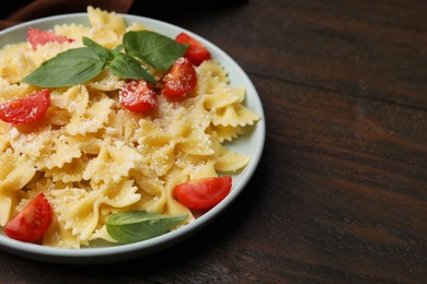 Tasty pasta with tomato, cheese and basil on wooden table. Space for text