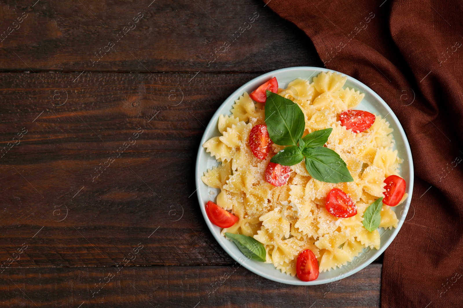 Photo of Tasty pasta with tomato, cheese and basil on wooden table, top view. Space for text