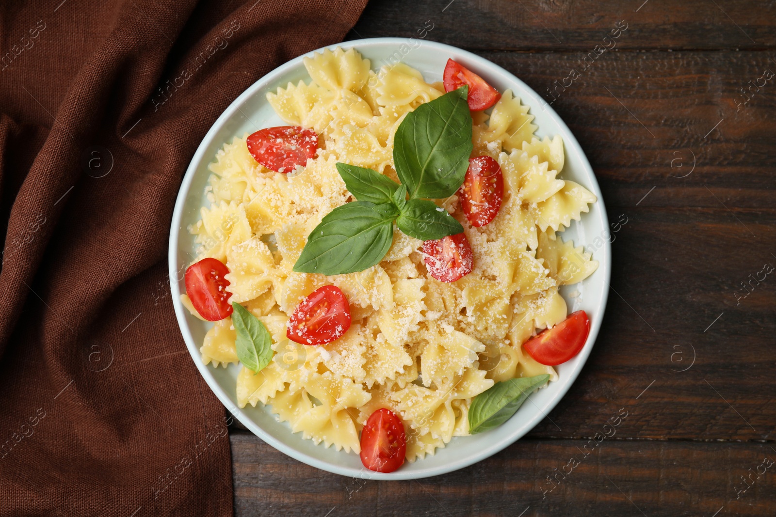 Photo of Tasty pasta with tomato, cheese and basil on wooden table, top view