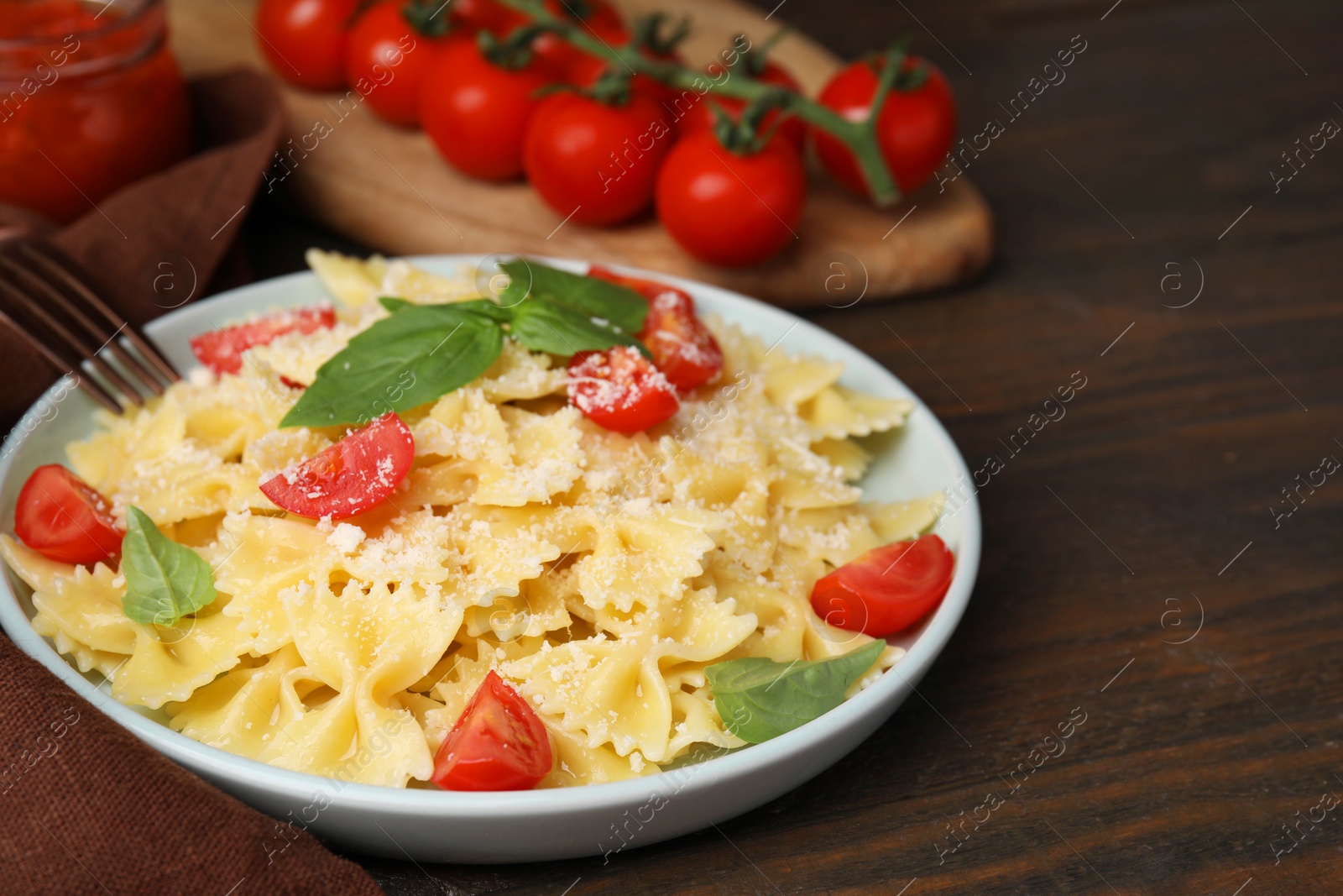 Photo of Tasty pasta with tomato, cheese and basil on wooden table, closeup