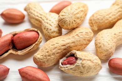 Fresh unpeeled peanuts on white wooden table, closeup