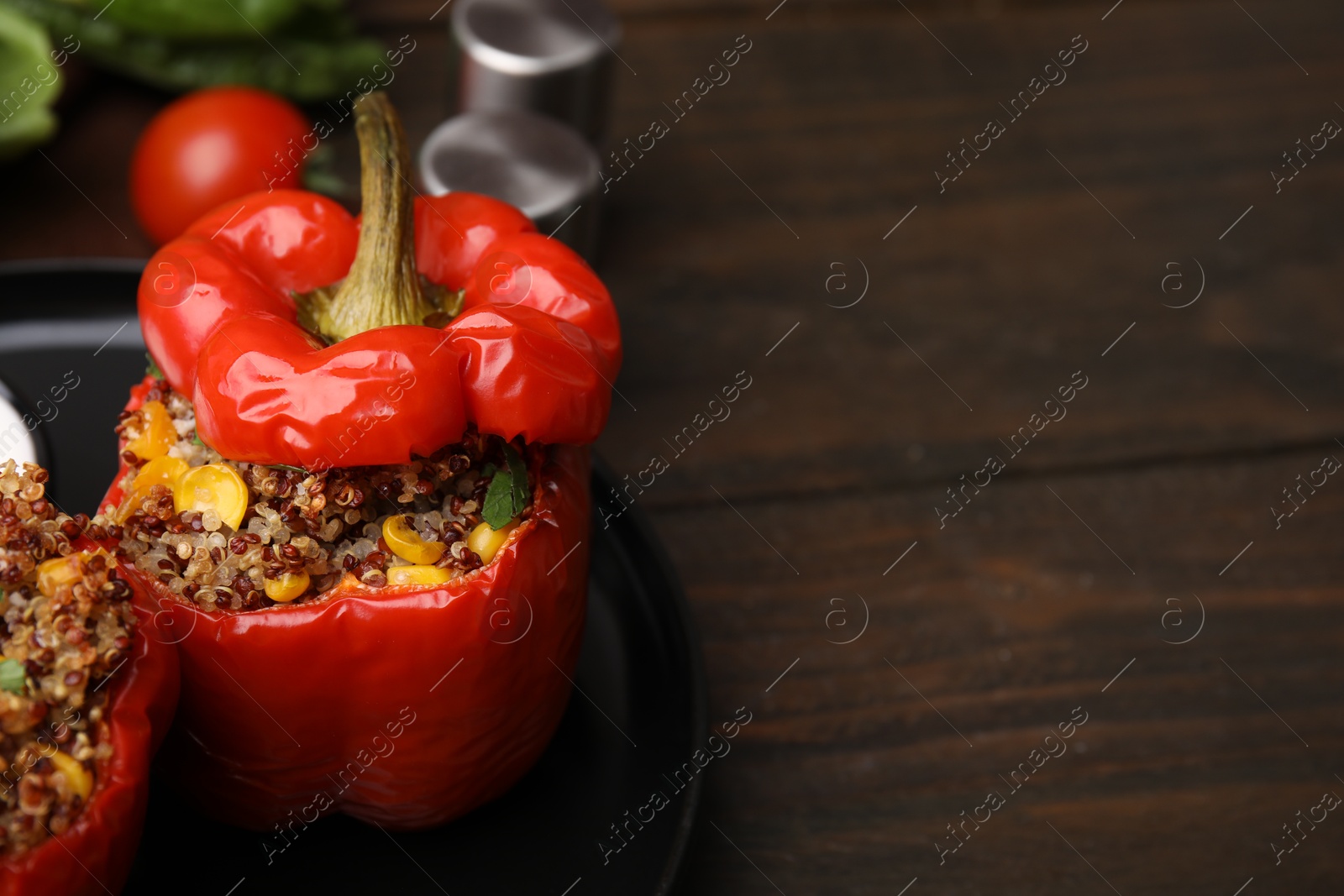 Photo of Quinoa stuffed peppers with corn on wooden table, closeup. Space for text