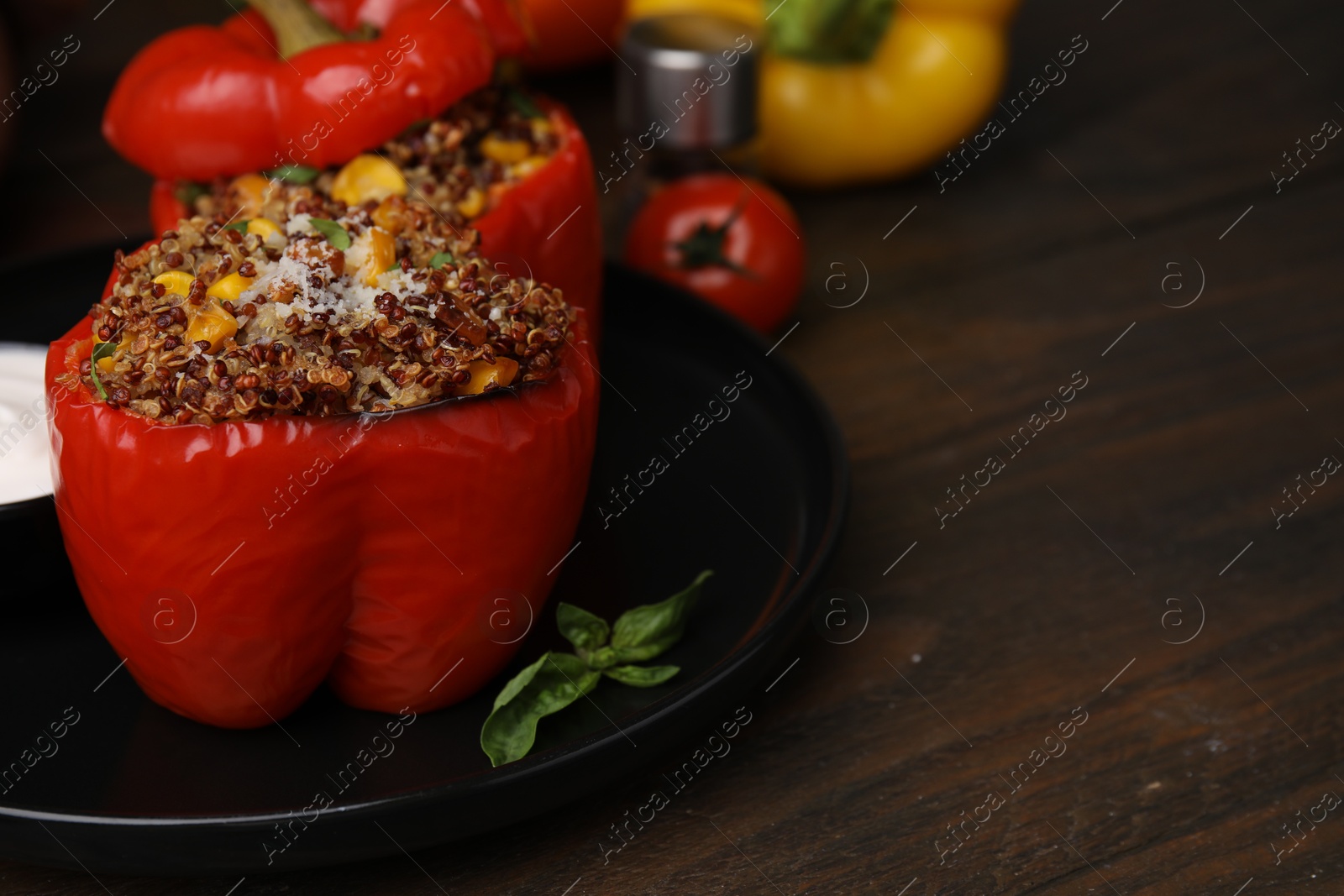 Photo of Quinoa stuffed peppers with corn and basil on wooden table, closeup. Space for text