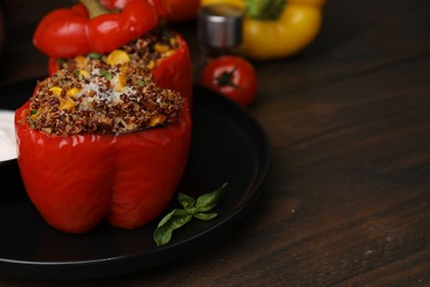 Photo of Quinoa stuffed peppers with corn and basil on wooden table, closeup. Space for text