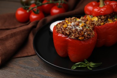 Photo of Quinoa stuffed peppers with corn and basil on wooden table, closeup