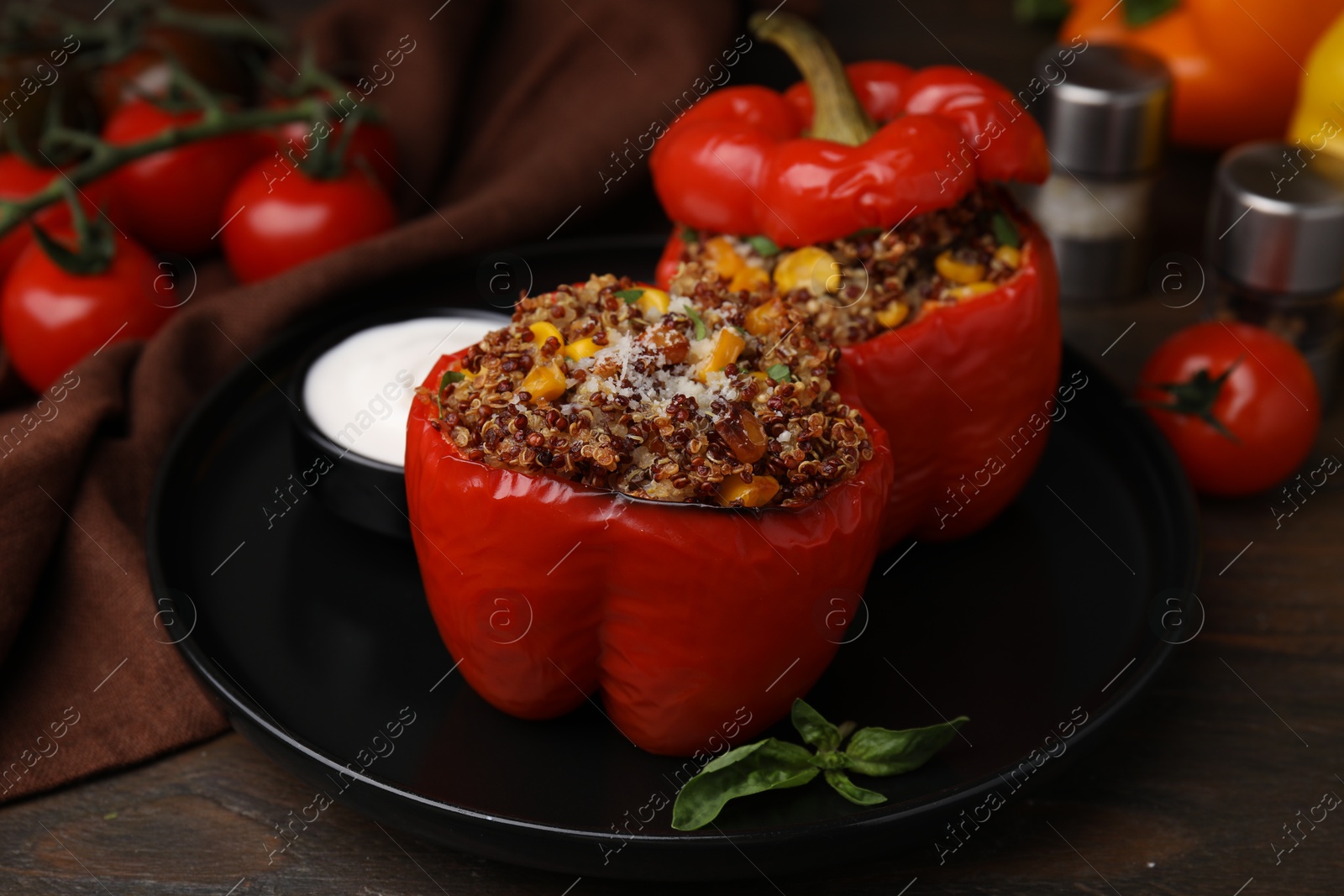 Photo of Quinoa stuffed peppers with corn, basil and sauce on wooden table