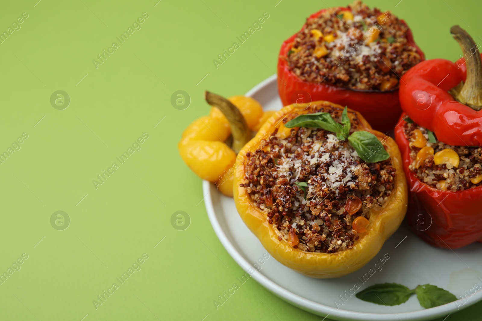 Photo of Quinoa stuffed peppers with corn and basil on light green table, closeup. Space for text