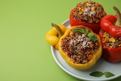 Photo of Quinoa stuffed peppers with corn and basil on light green table, closeup. Space for text