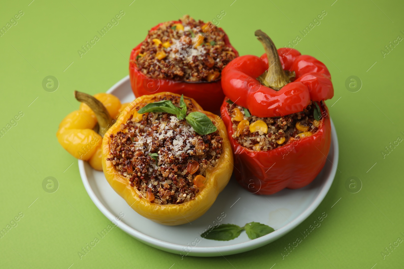 Photo of Quinoa stuffed peppers with corn and basil on light green table