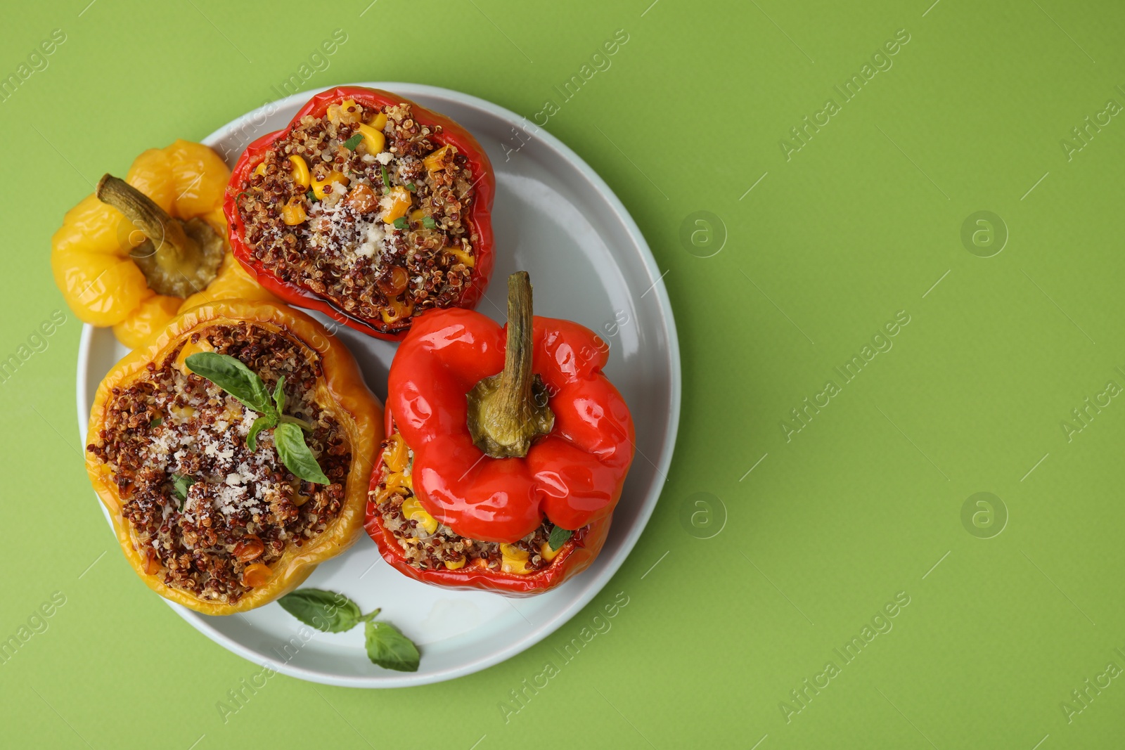 Photo of Quinoa stuffed peppers with corn and basil on light green table, top view. Space for text