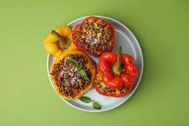 Photo of Quinoa stuffed peppers with corn and basil on light green table, top view