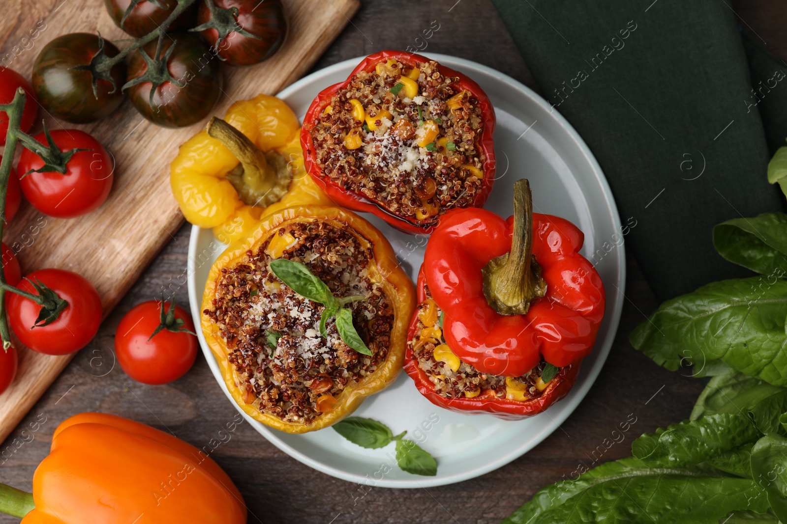 Photo of Quinoa stuffed peppers with corn and basil on wooden table, flat lay