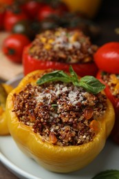 Photo of Quinoa stuffed peppers with corn and basil on wooden table, closeup