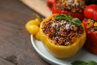 Photo of Quinoa stuffed peppers with corn and basil on wooden table, closeup. Space for text