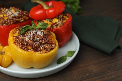 Photo of Quinoa stuffed peppers with corn and basil on wooden table, closeup. Space for text