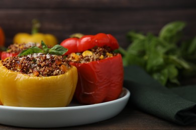 Photo of Quinoa stuffed peppers with corn and basil on wooden table, closeup. Space for text