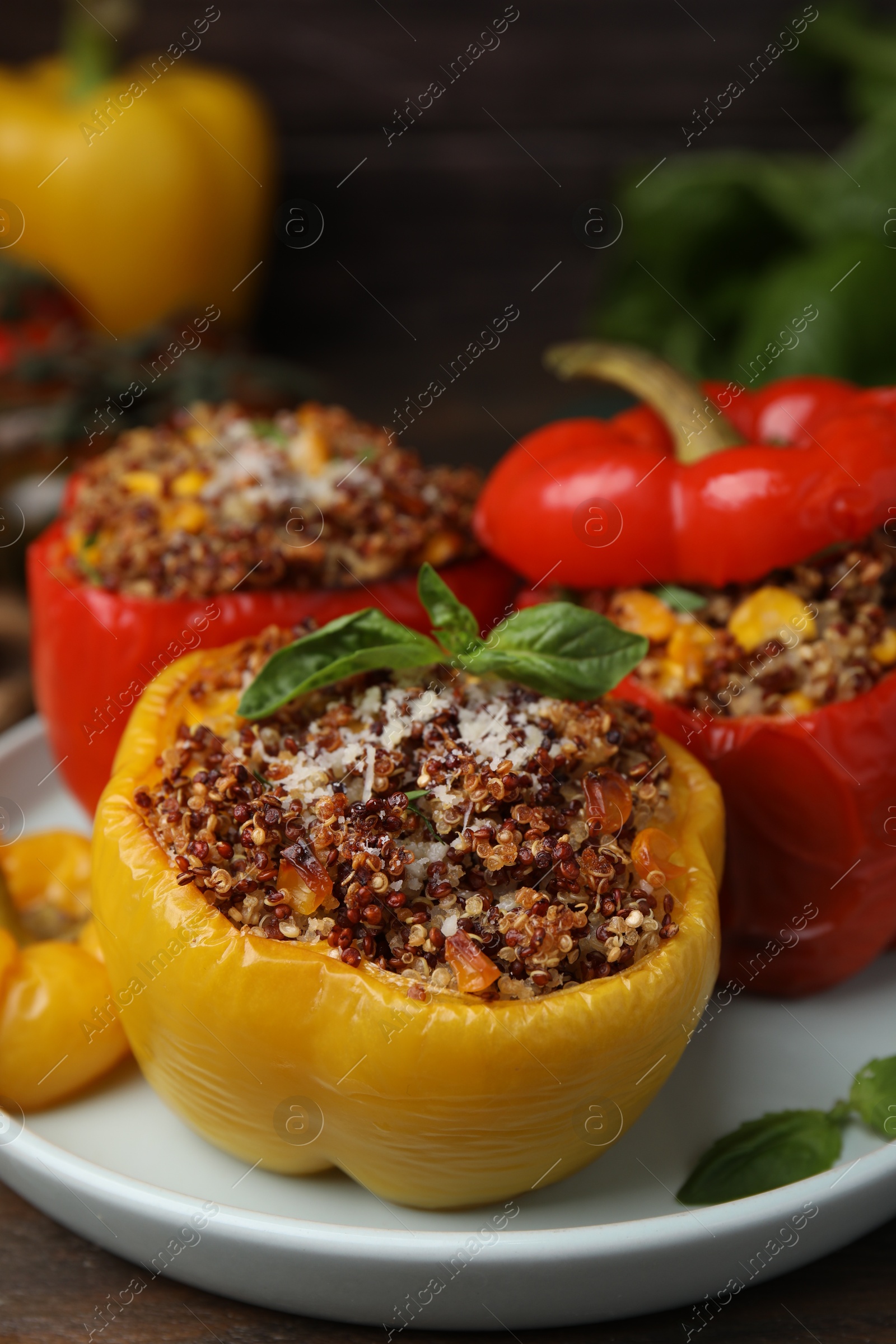 Photo of Quinoa stuffed peppers with corn and basil on wooden table, closeup