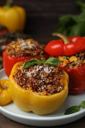 Photo of Quinoa stuffed peppers with corn and basil on wooden table, closeup